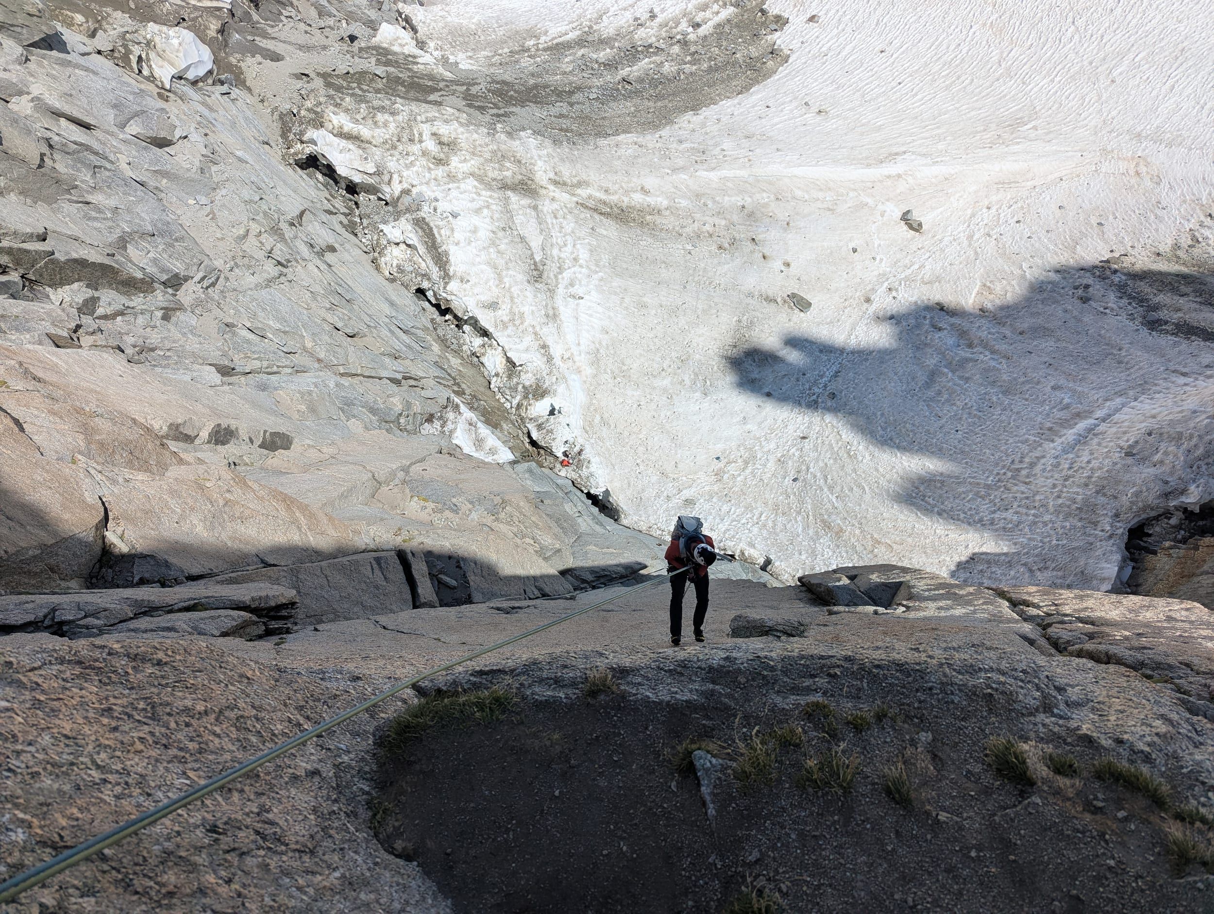 Kletterer beim Abseilen auf glatten Granitplatten hoch über dem Gletscher.