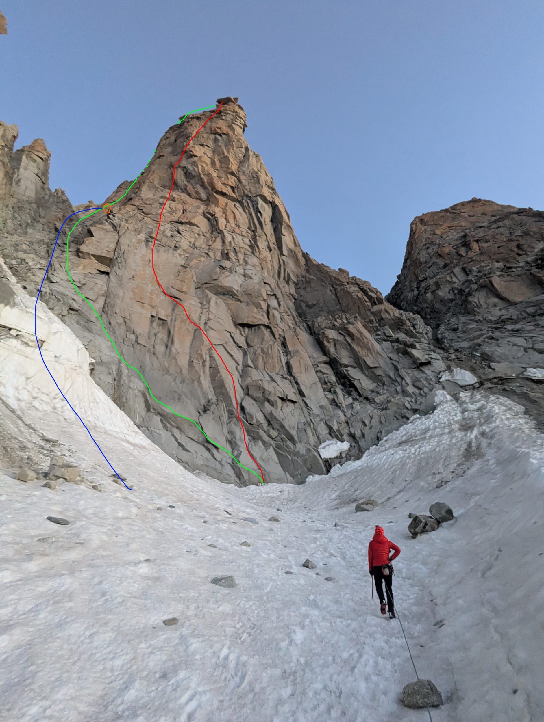 Die Südwand vom Wandfuß aus — in grün der ungefähre Routenverlauf, blau der originale Zustieg, orange der ehemalige Start der Route und rot der Abseilverlauf